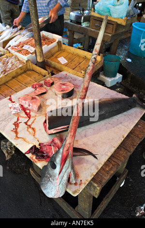 Le chef d'un petit poisson épée est séparée de son corps sur une table de coupe des poissonniers du marché de poissons Catane Sicile Italie Banque D'Images