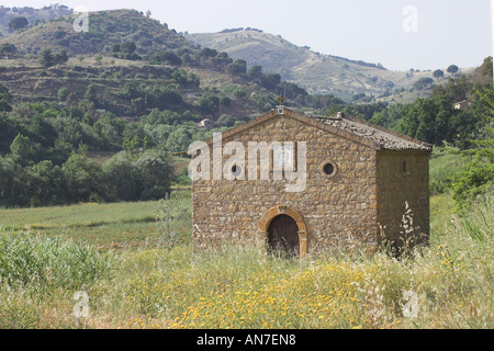 Une simple vieille église en pierre le définir un champ de fleurs sauvages jaune est situé dans une vallée entre les collines de la Sicile Banque D'Images