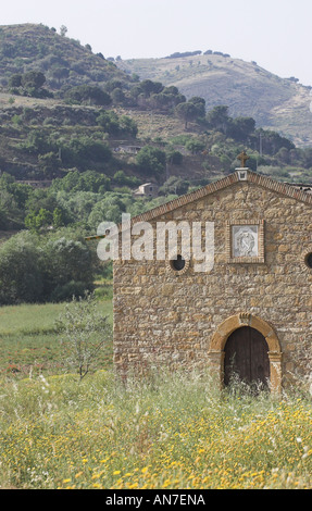 Une simple vieille église en pierre le définir un champ de fleurs sauvages jaune est situé dans une vallée entre les collines de la Sicile Banque D'Images