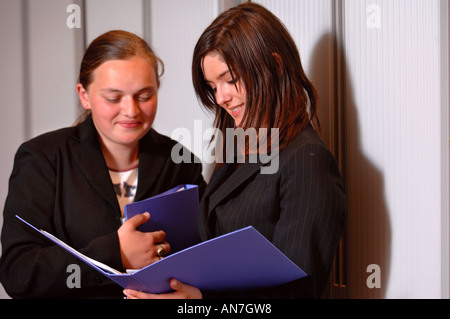 Deux ADOLESCENTES HOLDING FOLDERS DANS UN ENVIRONNEMENT DE BUREAU UK Banque D'Images