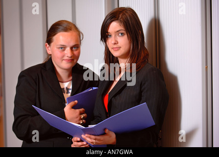 Deux ADOLESCENTES HOLDING FOLDERS DANS UN ENVIRONNEMENT DE BUREAU UK Banque D'Images