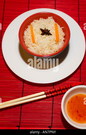 Repas de riz chinois bol sur un tapis bambou rouge réglage rythme avec des baguettes Banque D'Images