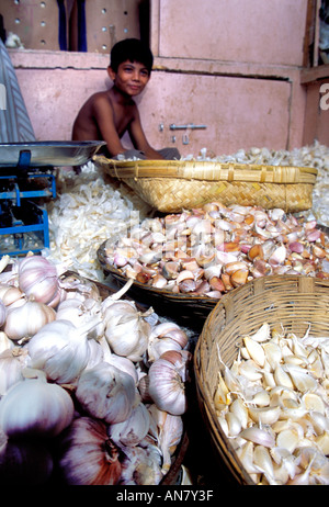 Paniers avec l'ail et un peu garçon vendeur tirant un sourire charmant marché Crawford Bombay Inde Maharashtra Banque D'Images