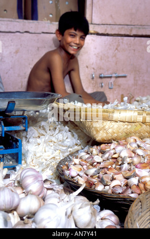 Paniers avec l'ail et un peu garçon vendeur tirant un sourire charmant marché Crawford Bombay Inde Maharashtra Banque D'Images