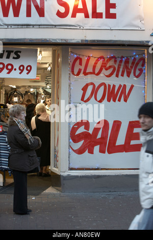 Femme debout à côté de la fermeture de la vente signer dans une vitrine avec man walking passé Dublin République d'Irlande Banque D'Images