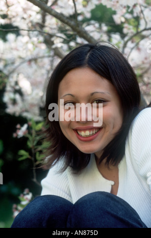 Portrait de 14 ans Caucasien Asiatique mixte femelle en face de fleurs de cerisier Banque D'Images