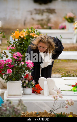 ESTORIL PORTUGAL Femme dans le cimetière prend les roses tombe d'un membre de la famille Banque D'Images