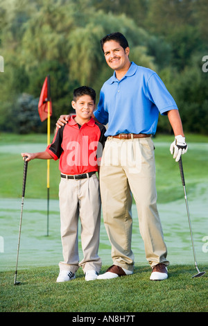 Hispanic father and son sur hugging on golf course Banque D'Images