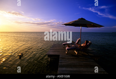 Au coucher du soleil avec parasol relaxant Ambergris Caye Belize MR Banque D'Images