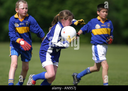 Jeune fille s'attaque à deux jeunes garçons pendant un match de football gaélique juniort à Belfast Banque D'Images