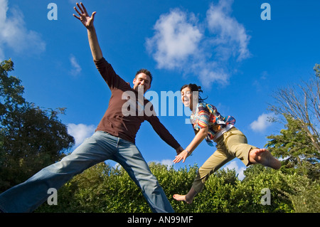 Portriat horizontale de jeunes adultes de race blanche au milieu de l'air contre un ciel bleu, de rebondir sur un trampoline. Banque D'Images