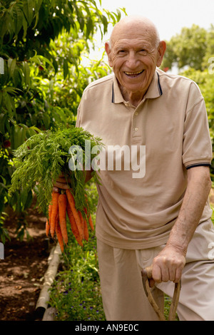 Portrait of a senior man holding a bunch of carrots Banque D'Images