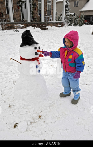 Les enfants à construire avec bonhomme de neige après un hiver mère Banque D'Images