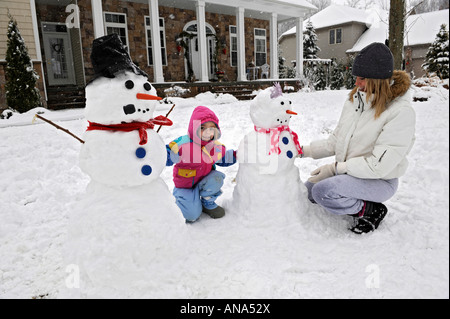 Les enfants à construire avec bonhomme de neige après un hiver mère Banque D'Images