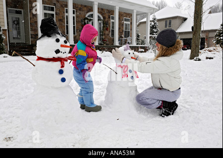 Les enfants à construire avec bonhomme de neige après un hiver mère Banque D'Images