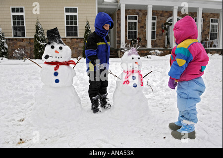 Les enfants à construire avec bonhomme de neige après un hiver mère Banque D'Images