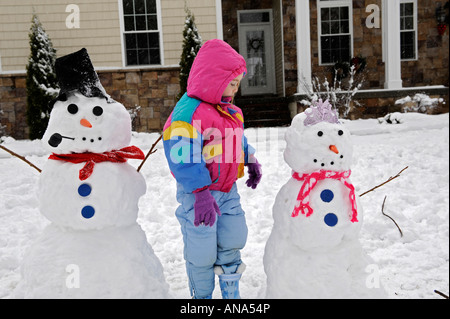 Les enfants à construire avec bonhomme de neige après un hiver mère Banque D'Images