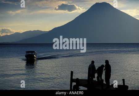 Les touristes à la fin d'une jetée qui se profile au coucher du soleil Panajachel Lac Atitlan Guatemala Bateau et volcan San Pedro au-delà Banque D'Images