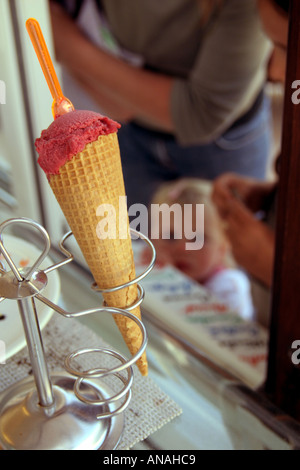 Cornet de crème glacée aux fraises avec cuillère dans la crème glacée en kiosque avec jeune fille à la recherche en prévision sur Normandie France Banque D'Images