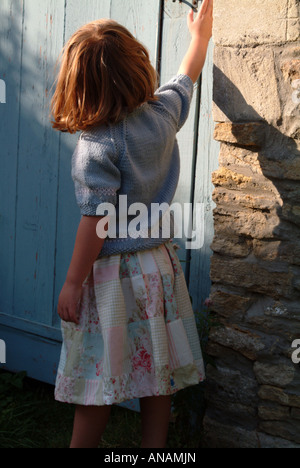 Petite fille d'atteindre pour ouvrir une porte Banque D'Images