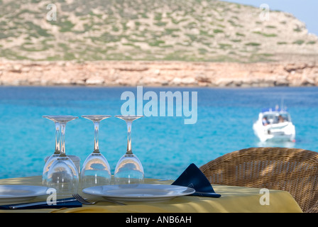 Restaurant sur la plage avec vue sur la mer turquoise avec un yacht en arrière plan à Platges de Comte, Ibiza Banque D'Images