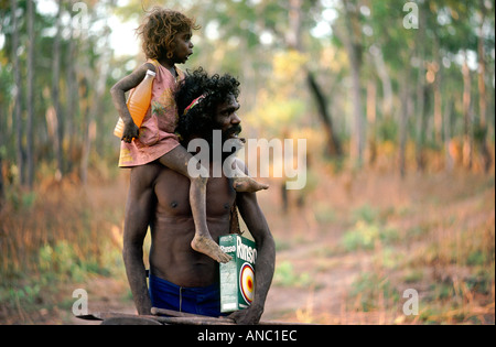 Charlie porte sa fille ses lances et de poudre à laver de nouveau à son camp à distance dans la brousse à Mormega La Terre d'Arnhem Banque D'Images