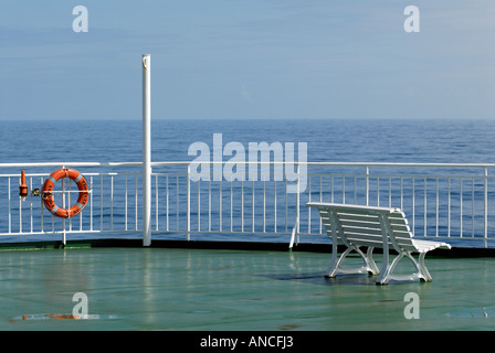 Un banc blanc sur le pont d'un paquebot avec une bouée de pendaison sur les grilles Banque D'Images