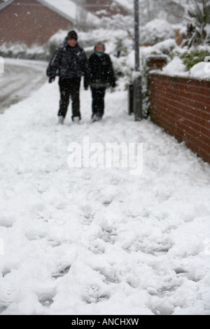 Traces de pas dans la neige le sentier d'une rue avec deux garçons marcher Banque D'Images