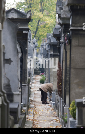 Une femme âgée a tendance à une tombe dans le cimetière du Père Lachaise à Paris, France Banque D'Images