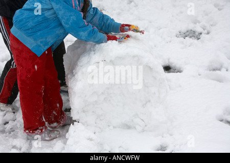 Deux enfants grand rouleau jusqu'à faire une boule de snowman Banque D'Images