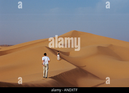 Les touristes l'ascension d'une dune de sable dans le désert du Sahara Maroc Banque D'Images