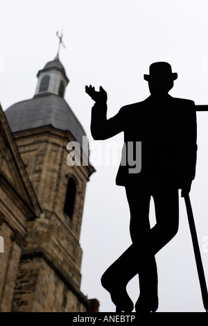 Découpe de métal d'un homme portant un costume et chapeau melon à l'extérieur d'un atelier de tailleur Français Banque D'Images