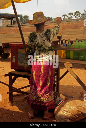 Femme autochtone en vêtements traditionnels colorés & straw hat vente de jus de fruits squeeze Poipet Cambodge Asie du sud-est Banque D'Images