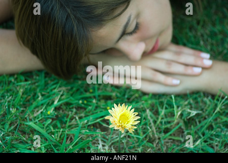 Woman lying on grass en regard de simple fleur jaune Banque D'Images