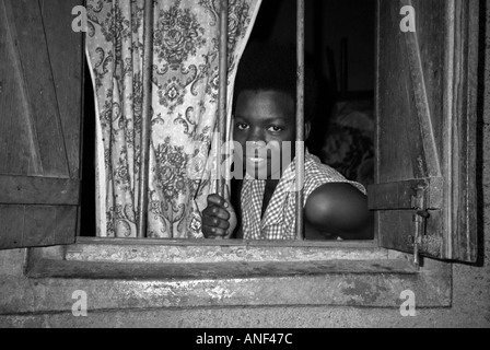 Souriante jeune femme du bidonville d'Acholy quart à la fenêtre de sa cabane en bois Kampala Ouganda Afrique de l'Est Banque D'Images