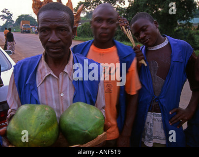 Groupe d'hommes vendeur de rue offrant un poulet rôti aux fruits et de la viande de boeuf à la route près de Tororo Ouganda Kenya Afrique de l'Est Banque D'Images