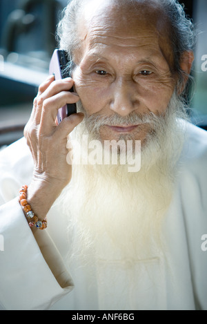 Un homme âgé en vêtements traditionnels chinois avec longue barbe, using cell phone Banque D'Images