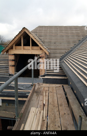 Maison individuelle en construction, y compris les travaux de toiture pignon lucarne, feutre, liteaux, voliges et échafaudage accès Banque D'Images