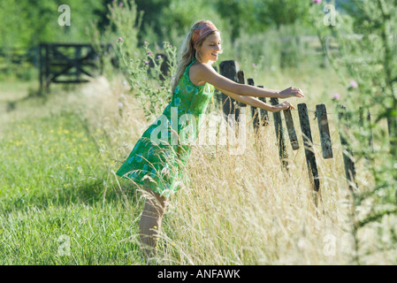 Young woman leaning against fence in rural field Banque D'Images