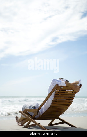 Homme assis dans une chaise, face à la mer Banque D'Images