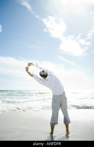 Jeune homme debout en surf, stretching, vue arrière Banque D'Images