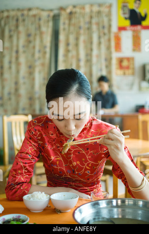 Jeune femme portant des vêtements traditionnels chinois, manger avec des baguettes Banque D'Images