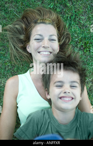 Mère et fils, garçon couché sur le dessus de la femme, rire, allongé sur l'herbe, high angle view Banque D'Images
