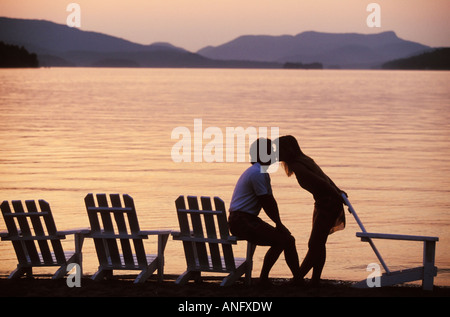 Jeune couple baiser sur la plage au coucher du soleil sur le Lac Tremblant, à Mont Tremblant, au nord de Montréal, Québec, Canada. Banque D'Images