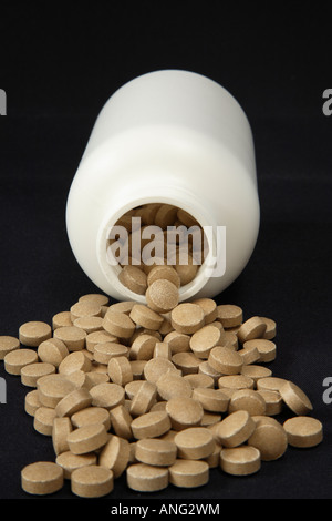 Bouteille de blanc sur le côté déversant toute l'épaisseur des comprimés tacheté de brun en grand bassin avant qu'il Banque D'Images