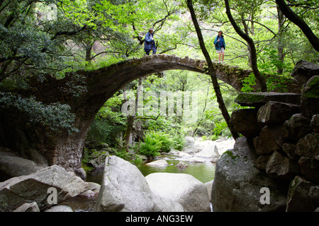 Randonneurs sur le pont de zaglia pont sur la rivière de spelunca Banque D'Images