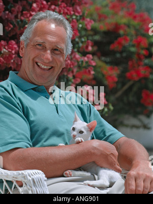 L'âge de la retraite l'homme lui-même au soleil dans le jardin avec un chaton Banque D'Images