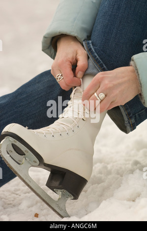 Une jeune femme lui chausse ses patins à glace Banque D'Images