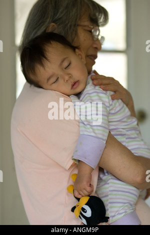 Bébé tient à son lovey en étant maintenu par sa grand-mère. Banque D'Images