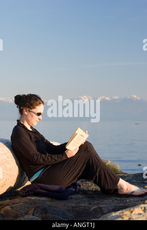 Une femme lisant un livre sur la plage, près de Victoria, Vancouver Island, British Columbia, Canada. Banque D'Images